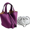 Lila Leder-Eimertasche mit Reißverschluss und brauner Futter neben einer weißen Schnurtasche.