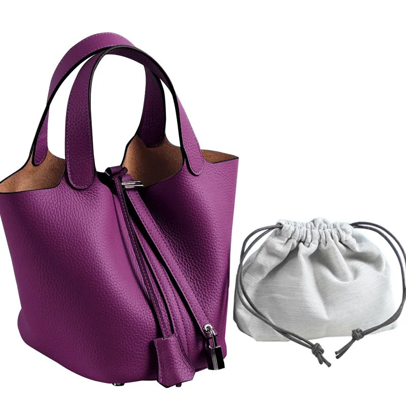 Lila Leder-Bucket-Bag mit Reißverschluss und brauner Futter neben einer weißen Schnurtasche.