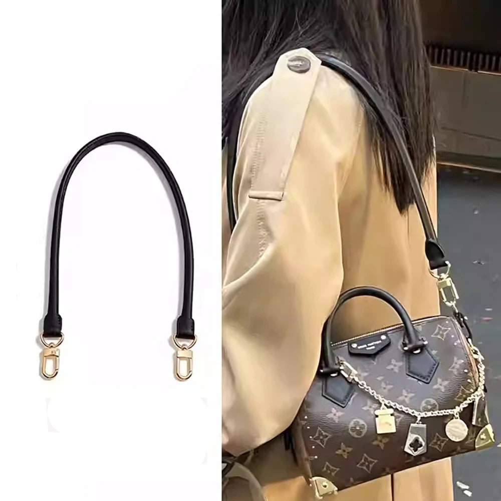 A close-up of a brown cowhide leather shoulder bag with a black strap and gold hardware.