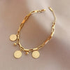 A gold stainless steel charm bracelet featuring a portrait pendant and various circular charms.