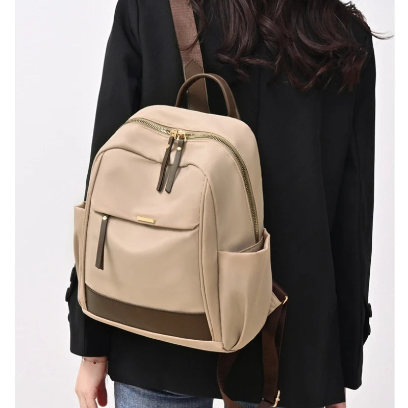 A beige lightweight nylon travel backpack with brown straps worn by a person.