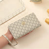 A beige patterned zipper wallet is held in a hand next to a white mesh storage tray.