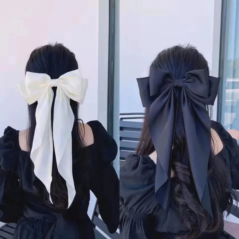 A woman with long dark hair wearing a large black silk bow accessory.