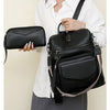 A woman holds a black retro PU leather travel backpack with tassel detail against a light background.