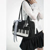 A woman holds a black and white piano print crossbody bag with a strap featuring musical note embroidery.