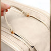 A hand is opening a beige PU leather travel makeup organizer featuring double zippers.