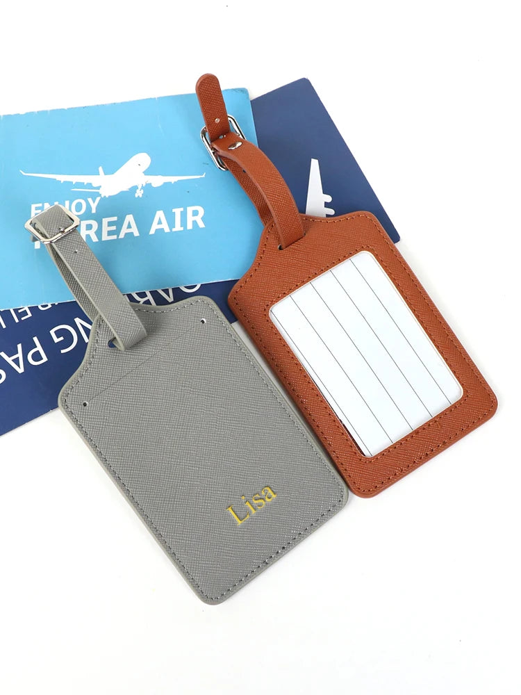 A set of two custom PU leather luggage tags, one gray and one brown, featuring a cross-pattern detail.