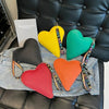 Colección de carteras de monedas en forma de corazón de PU amarillo, verde y naranja sobre una camisa vaquera con un libro.