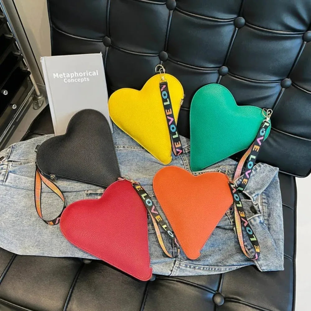 Colección de carteras de monedas en forma de corazón de PU amarillo, verde y naranja sobre una camisa vaquera con un libro.