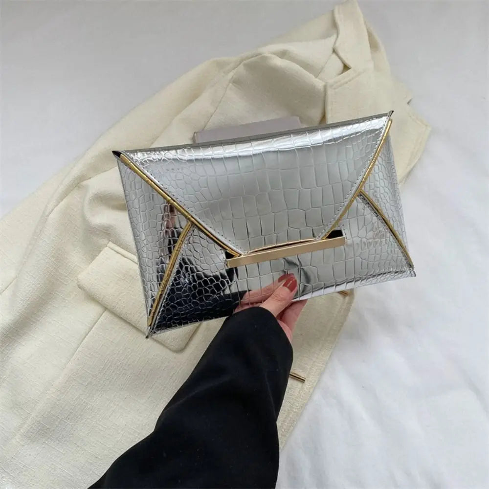 Silver crocodile pattern coin purse clutch held by a hand against a cream blazer.