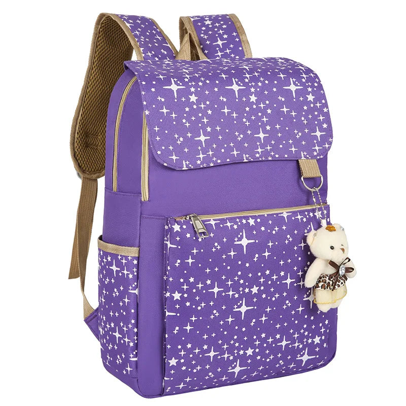 A purple canvas student backpack decorated with white stars and featuring a small teddy bear charm.