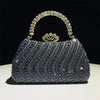 A dark gray crystal-embellished evening clutch bag with a gold crown clasp and chain strap.