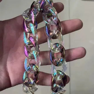 A close-up of a colorful resin bag strap and purse charm made of iridescent, swirling material.