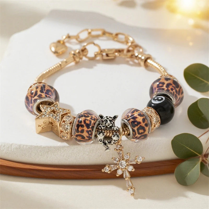 Gold and black beaded bracelet featuring leopard print accents and a silver cross charm.