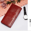 A deep red genuine leather clutch wallet placed next to a black wristwatch on a white background.