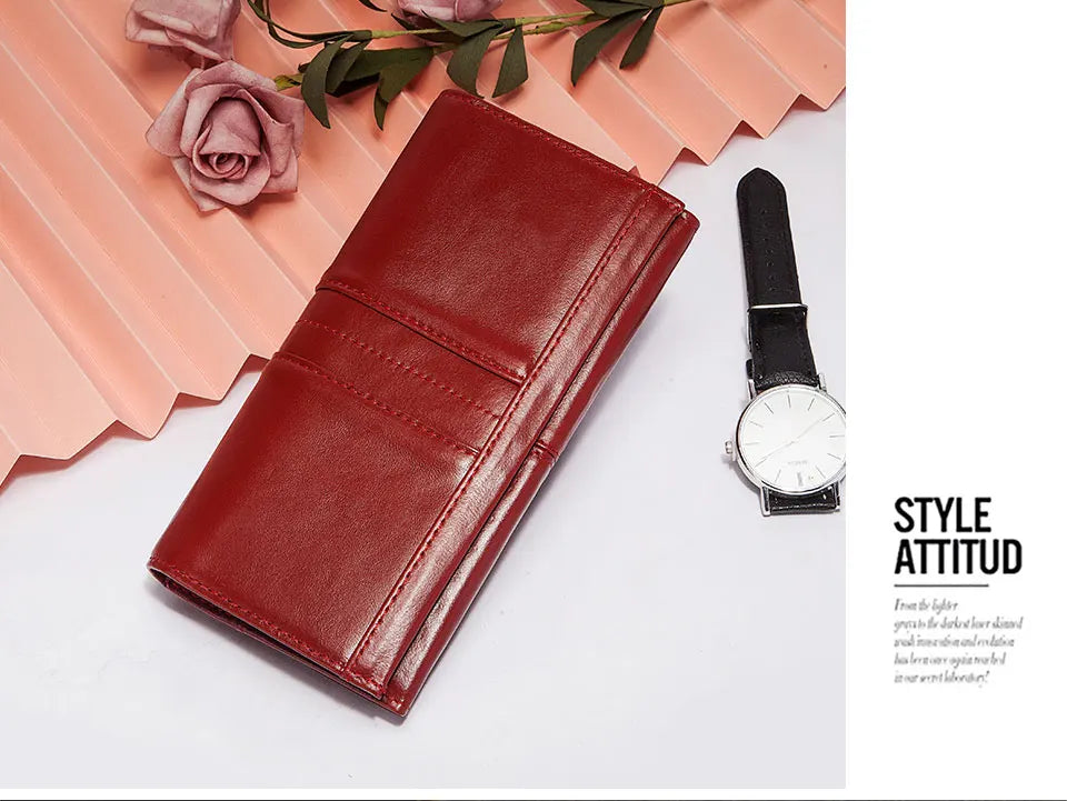 A deep red genuine leather clutch wallet placed next to a black wristwatch on a white background.