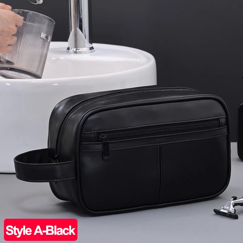A black PU leather travel toiletry bag resting on a gray surface next to a white sink.