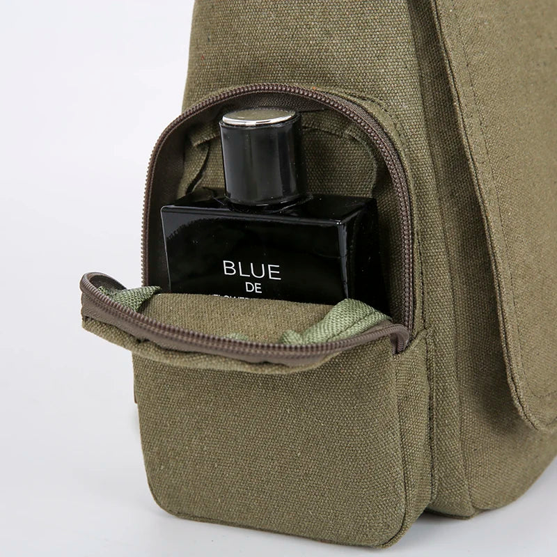 A dark glass bottle labeled BLUE DE is stored inside a olive green canvas messenger bag.