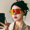 Una mujer vistiendo gafas de ciclismo con tinte naranja contra un fondo claro.