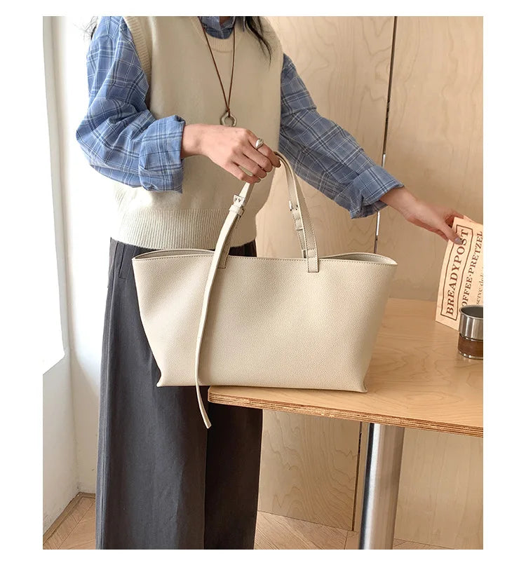Une femme tient un sac à main en similicuir beige décontracté dans un cadre brun clair.
