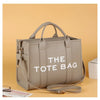 Sac cabas luxe en PU beige avec sangles en cuir, présenté sur un fond brun clair.