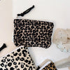A black and beige leopard print cosmetic bag is shown on a white surface.