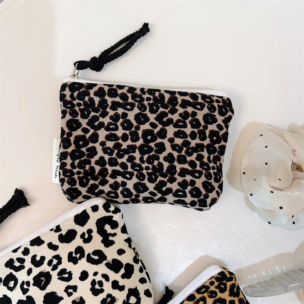 A black and beige leopard print cosmetic bag is shown on a white surface.