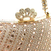 A close-up of a crystal-embellished gold clutch bag with a crown clasp and a gold chain strap.