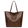 A brown crocodile print tote bag with a leather strap shown from the front.