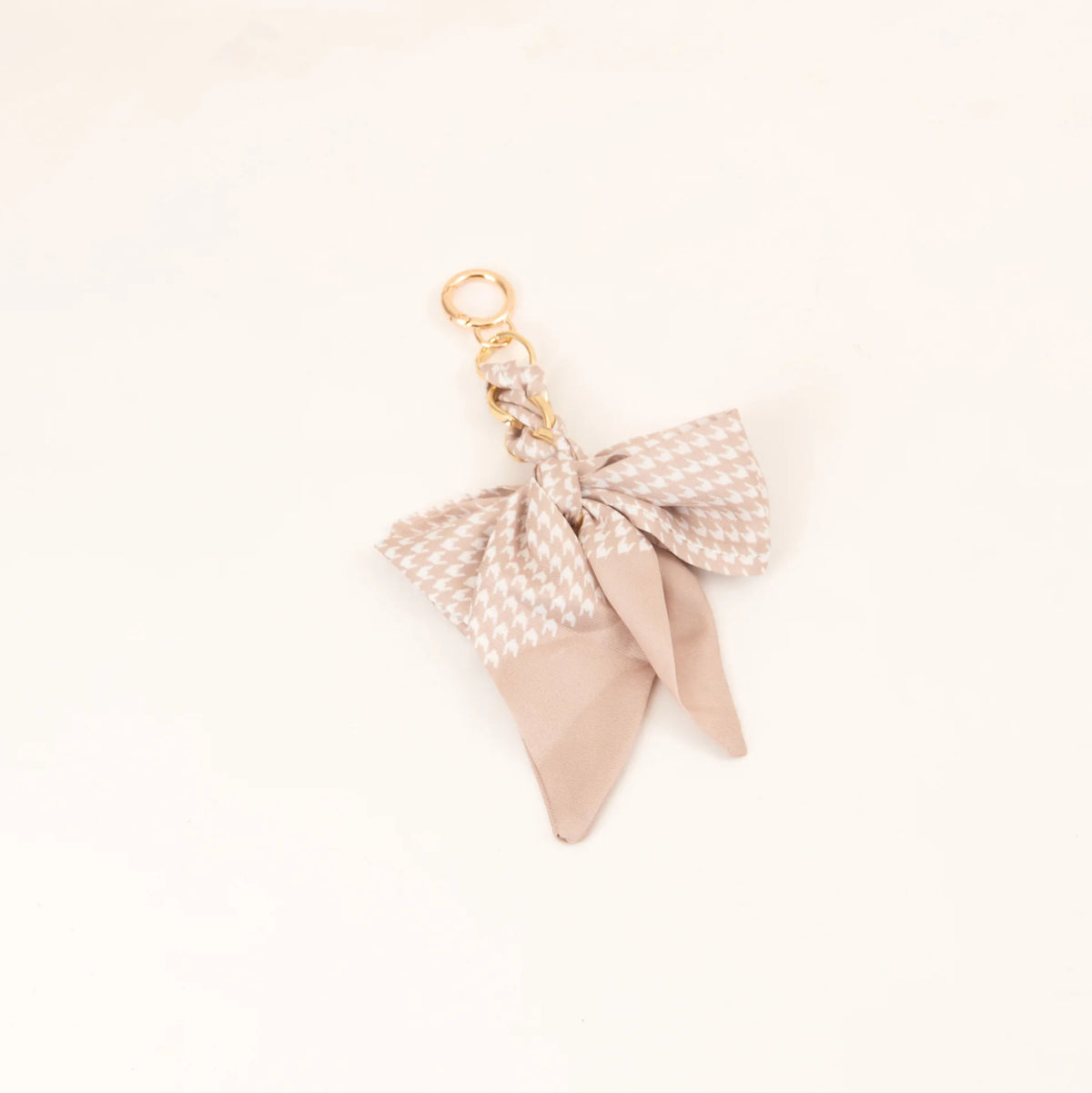 Lazo de cinta de seda beige atado en un nudo con anillo de llavero dorado.
