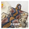 A close-up of an elegant retro crossbody bag featuring a brown and blue snakeskin pattern on a light background.