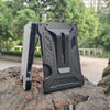 A gray slim aluminum metal ID card wallet resting on a rough, dark rock outdoors.