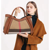 Ein Model hält eine Karamell-Karo-Kuhleder-Tasche vor sich und trägt einen braunen Mantel.