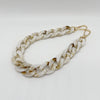 A silver-toned chain bracelet made of white and beige marbled acrylic.
