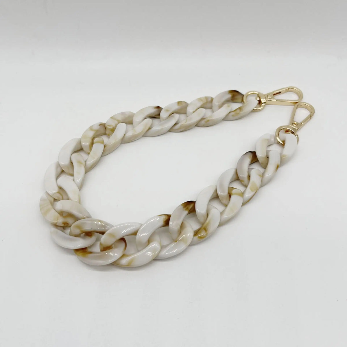 A silver-toned chain bracelet made of white and beige marbled acrylic.