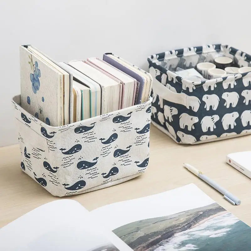 A white and black patterned storage basket filled with stacked books and a separate tray of small cylindrical items.