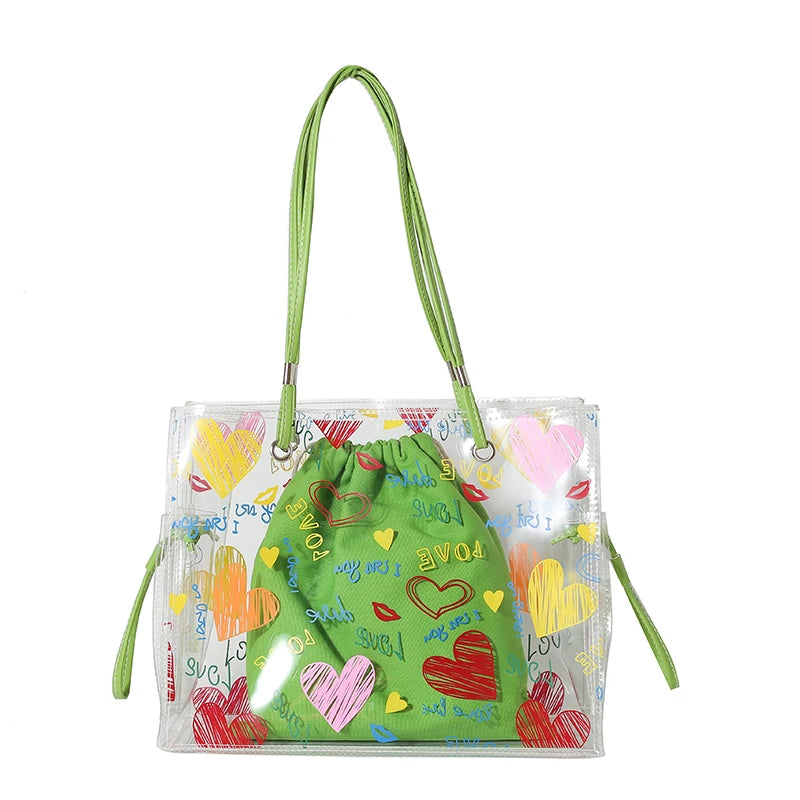 A clear plastic shoulder bag with a green fabric lining and yellow heart decorations, featuring long straps.