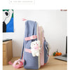 A light blue nylon backpack set featuring a pink and white cartoon bear design, displayed on a wooden surface.