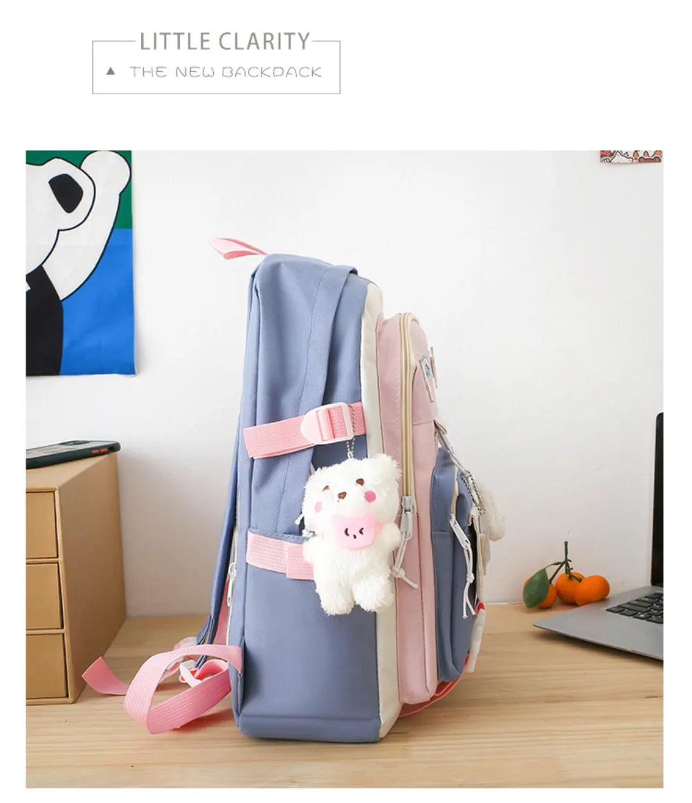 A light blue nylon backpack set featuring a pink and white cartoon bear design, displayed on a wooden surface.