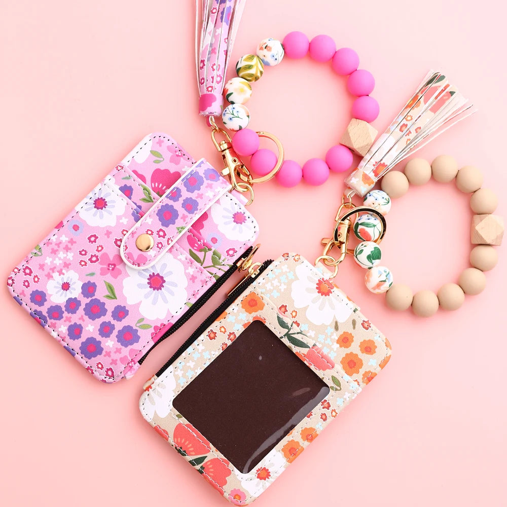 A pink silicone bead and PU leather key chain wallet with floral patterns and a beaded bracelet.