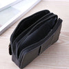 A black PU leather multi-function waist bag with zippered compartments resting on a light wooden surface.