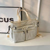 A cream textured corduroy tote bag with adjustable straps resting on a white surface.