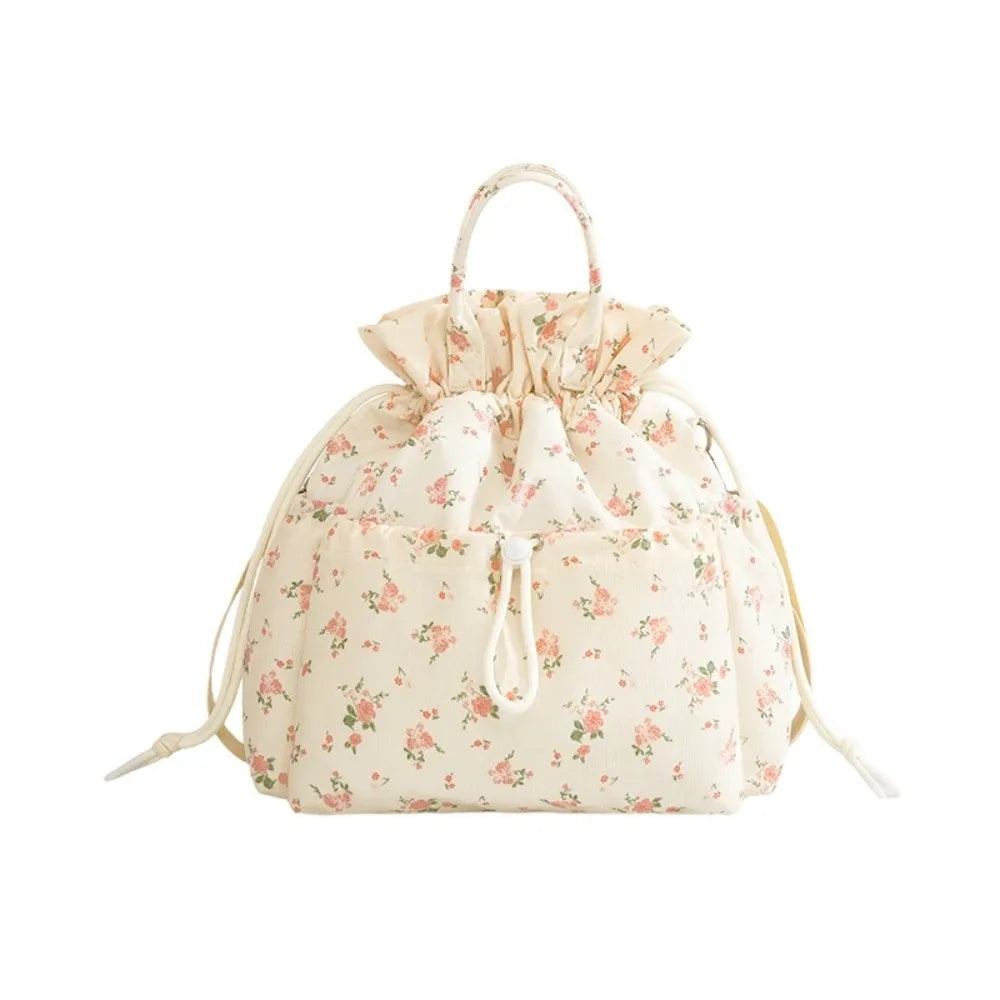 A light pink floral patterned insulated waterproof lunch bag with a drawstring closure and light beige fabric.