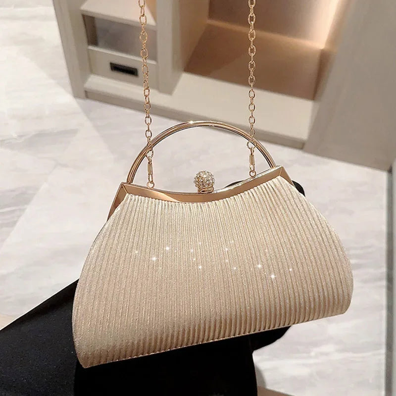 A beige pleated glitter evening handbag with a top handle and gold chain strap displayed against a light background.