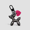 A black balloon dog keychain charm with a pink tag hanging from a loop.
