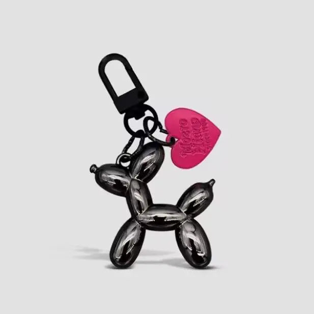 A black balloon dog keychain charm with a pink tag hanging from a loop.