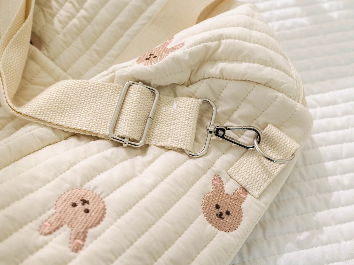 لقطة مقربة لحقيبة حفاضات مبطنة بالكريمة ذات حمالات بلون التان وقفل فضي.