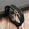 A black leather bracelet featuring multiple layers of black beads and a silver tiger eye charm resting on a wooden surface.