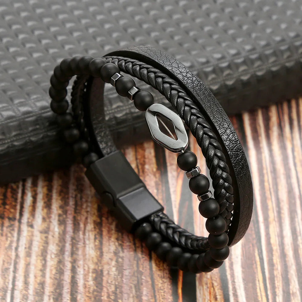 A black leather bracelet featuring multiple layers of black beads and a silver tiger eye charm resting on a wooden surface.