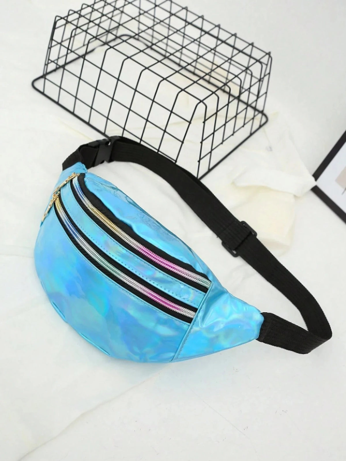 A bright blue holographic sequin waist bag with a black adjustable strap is displayed on a white surface.